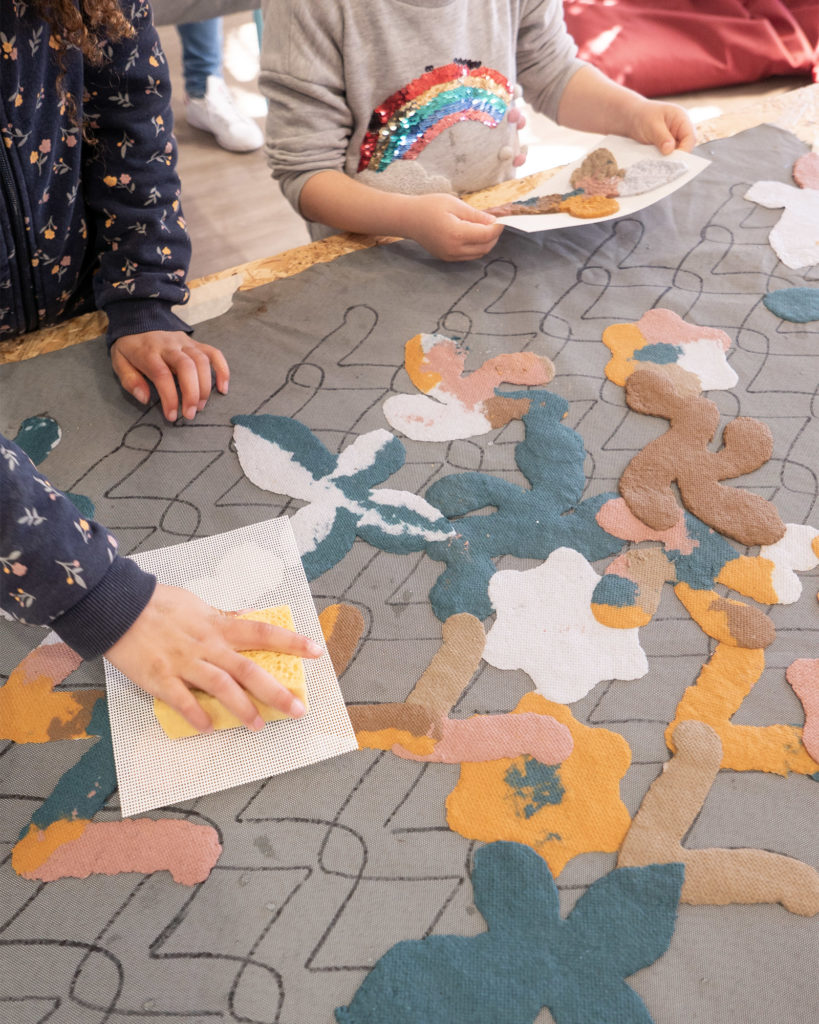 Two kids at the table pressing their shapes on the fresco