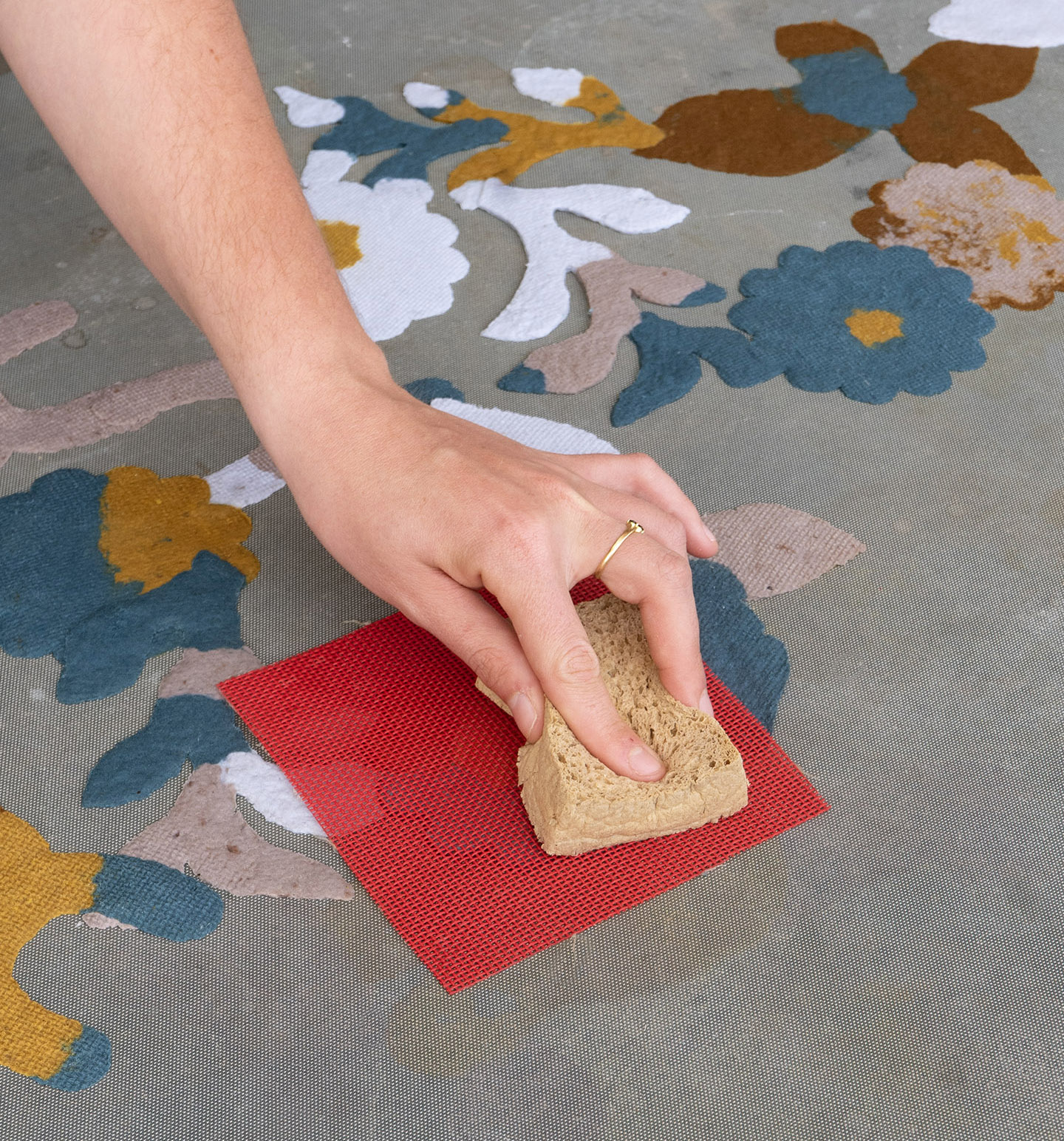 hand pressing a sponge to absorb the water from the recycled paper landscape in the making